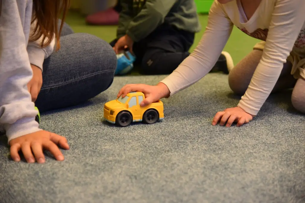 Kinder spielen mit einem gelben Spielzeugauto