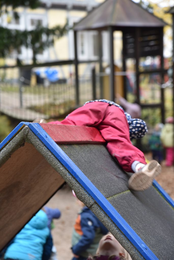 Kind liegt auf dem Dach von einem Spielhaus auf dem Spielplatz